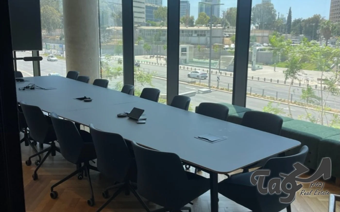 חדר ישיבות עם שולחן ארוך, רצפת עץ בדוגמת אדרה וחלונות לכיוון ציר בגין
