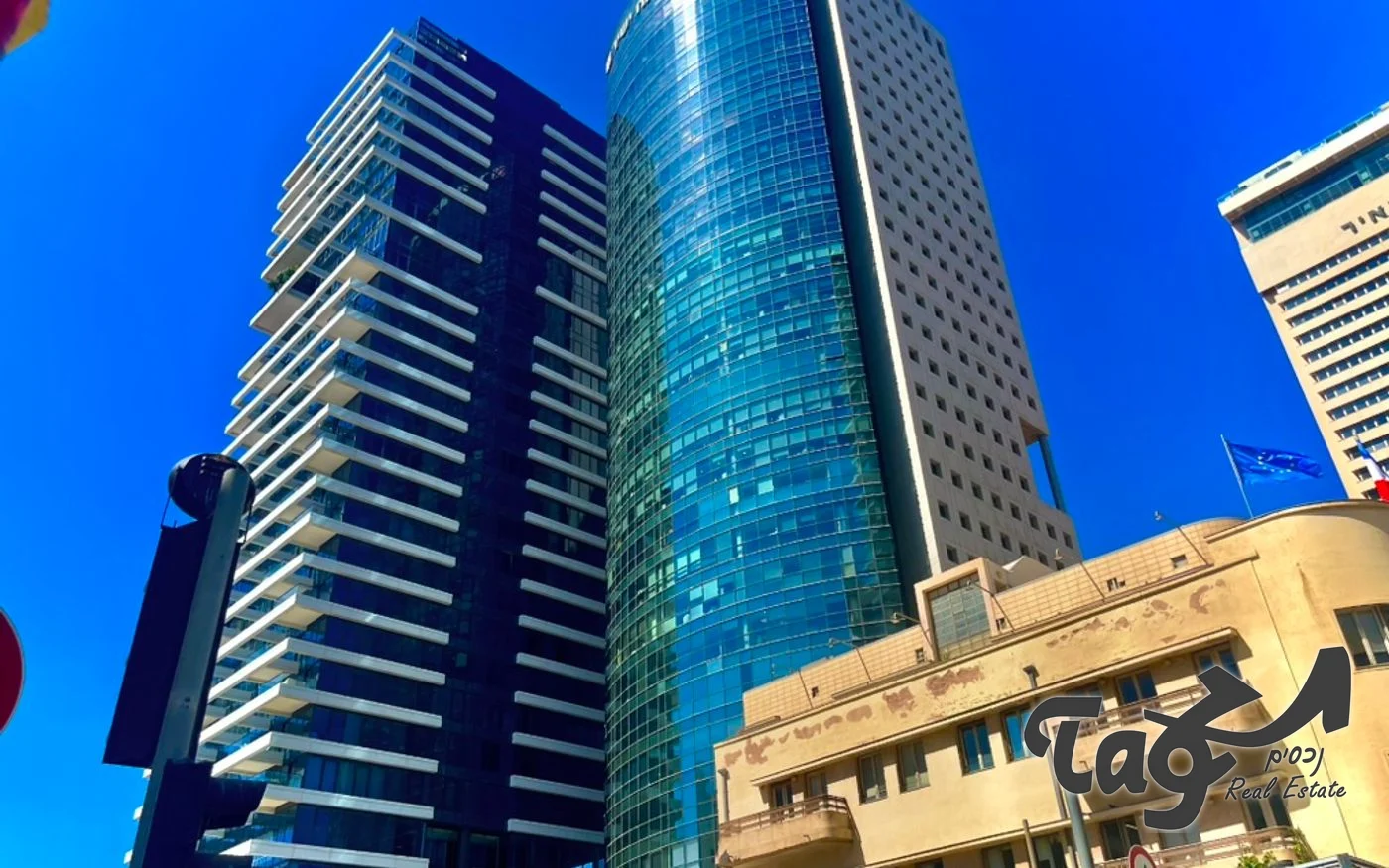 מגדל הזכוכית המעוגל בין מגדלים נוספים ובניין לשימור