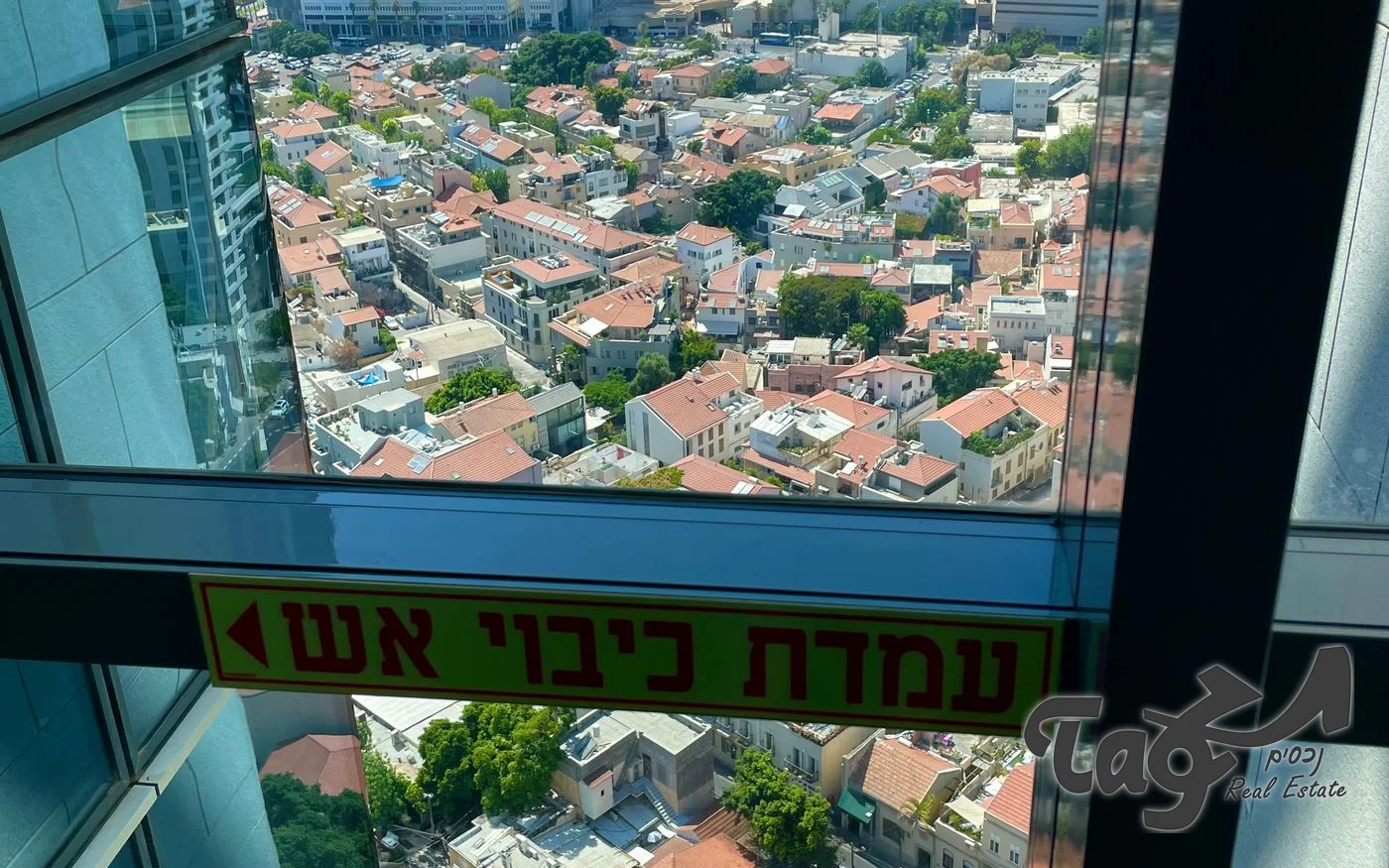 נוף מקומה גבוהה אל גגות רעפים של שכונה ותיקה, מבעד לחלון