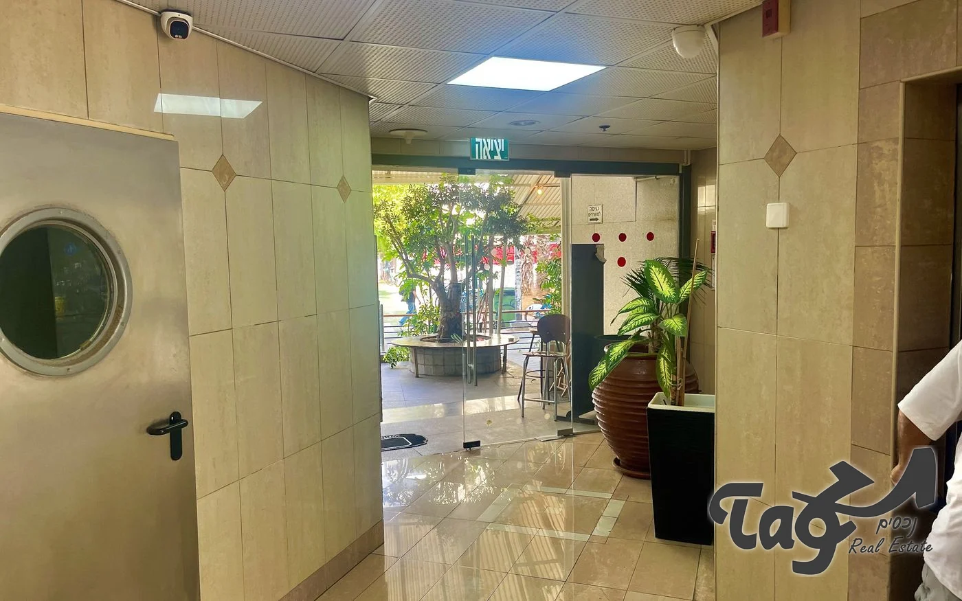 המעבר מהלובי לכניסת הבניין, עם קירות אבן בהירה ורצפה מבריקה