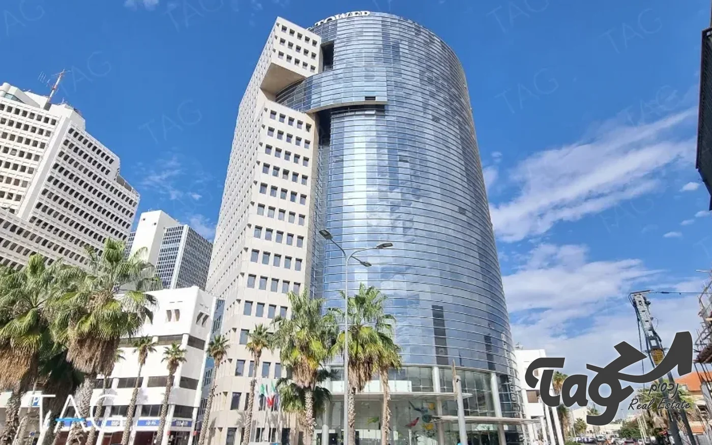 מגדל הזכוכית המעוגל מהרחוב, עם דקלים לפניו