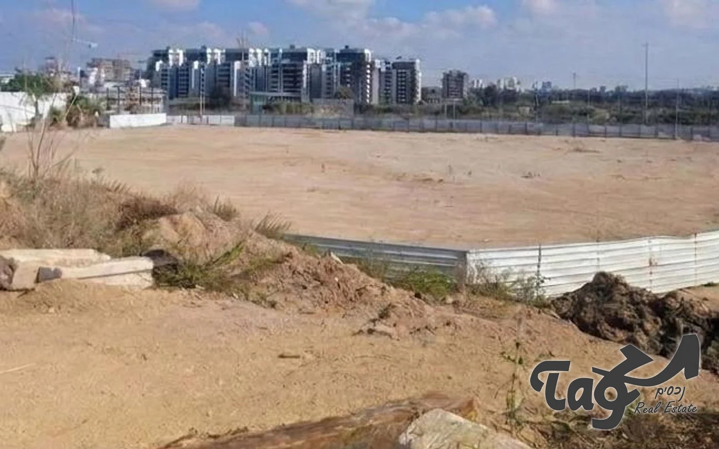 קרקע פנויה ברמת השרון, עם גדר ובניינים רבי קומות ברקע