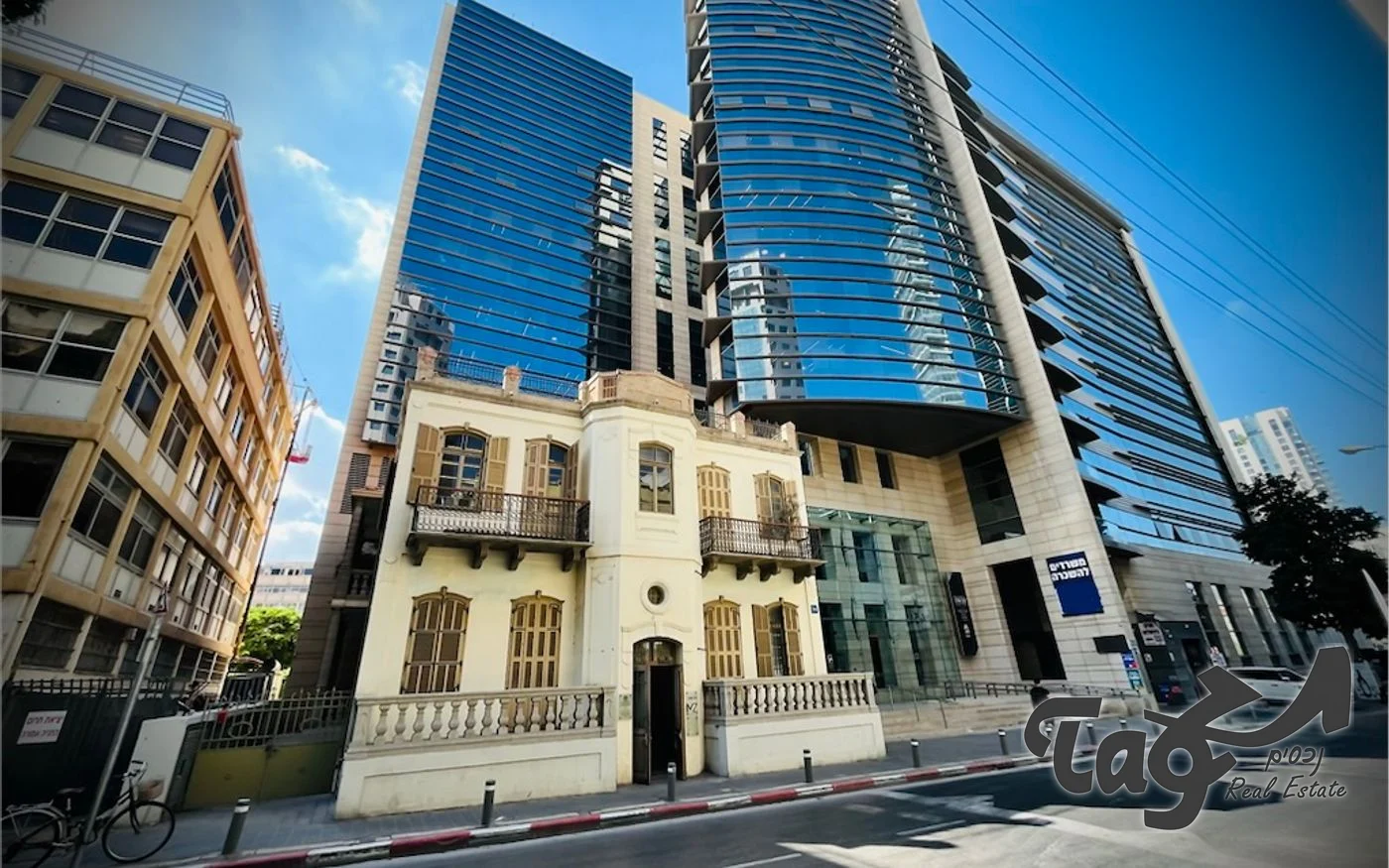 הבניין ההיסטורי בין מגדלי זכוכית גבוהים, מבט מהמדרכה
