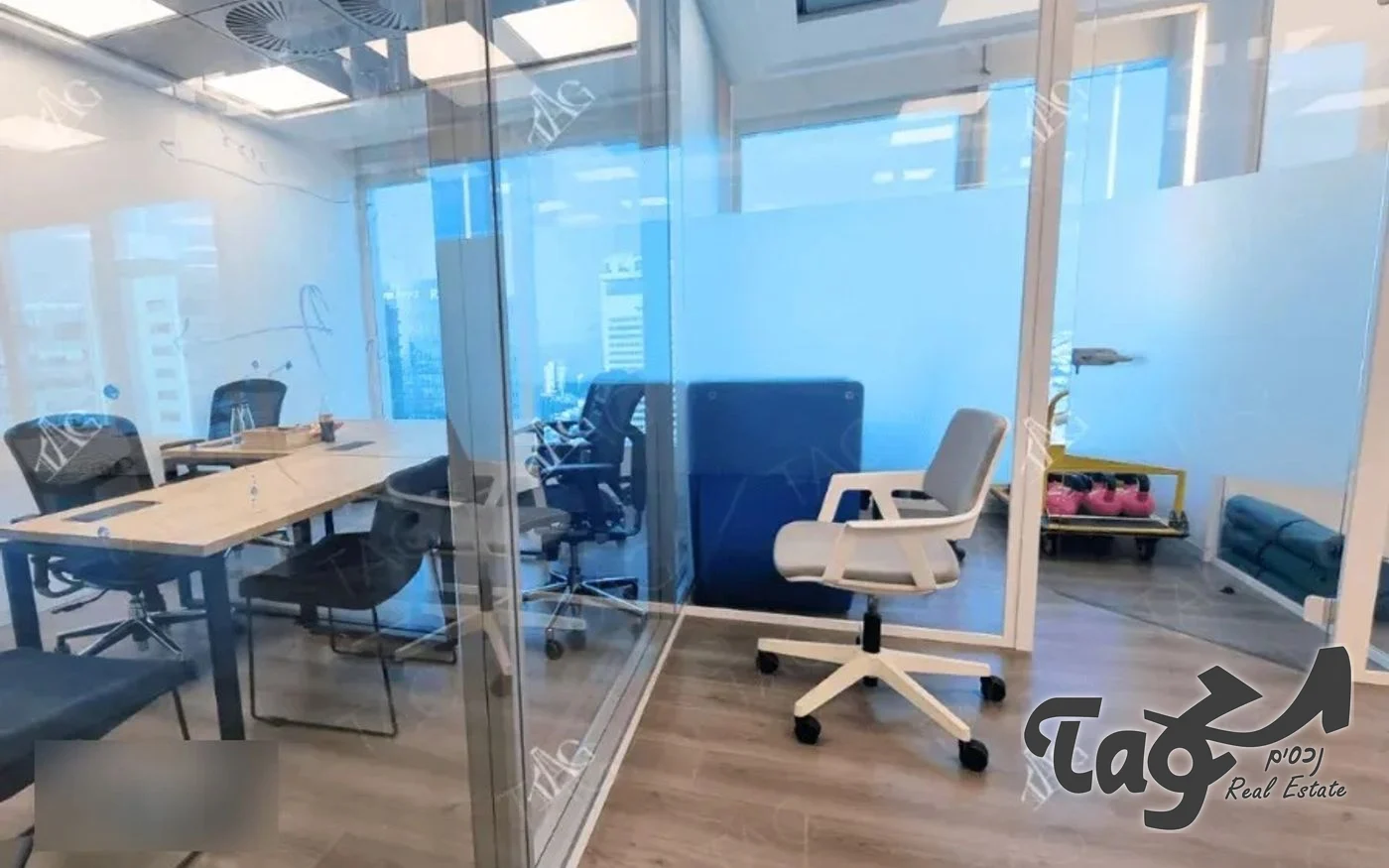 חדר ישיבות מזוגג עם קירות זכוכית, שולחן עץ ארוך וכיסאות משרד