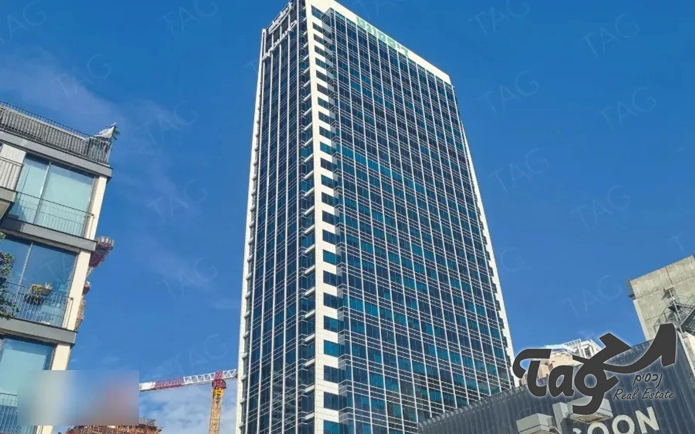 מגדל דיסקונט מבחוץ בצילום מלמטה: מגדל משרדים גבוה עם חזית זכוכית כהה ופסים לבנים