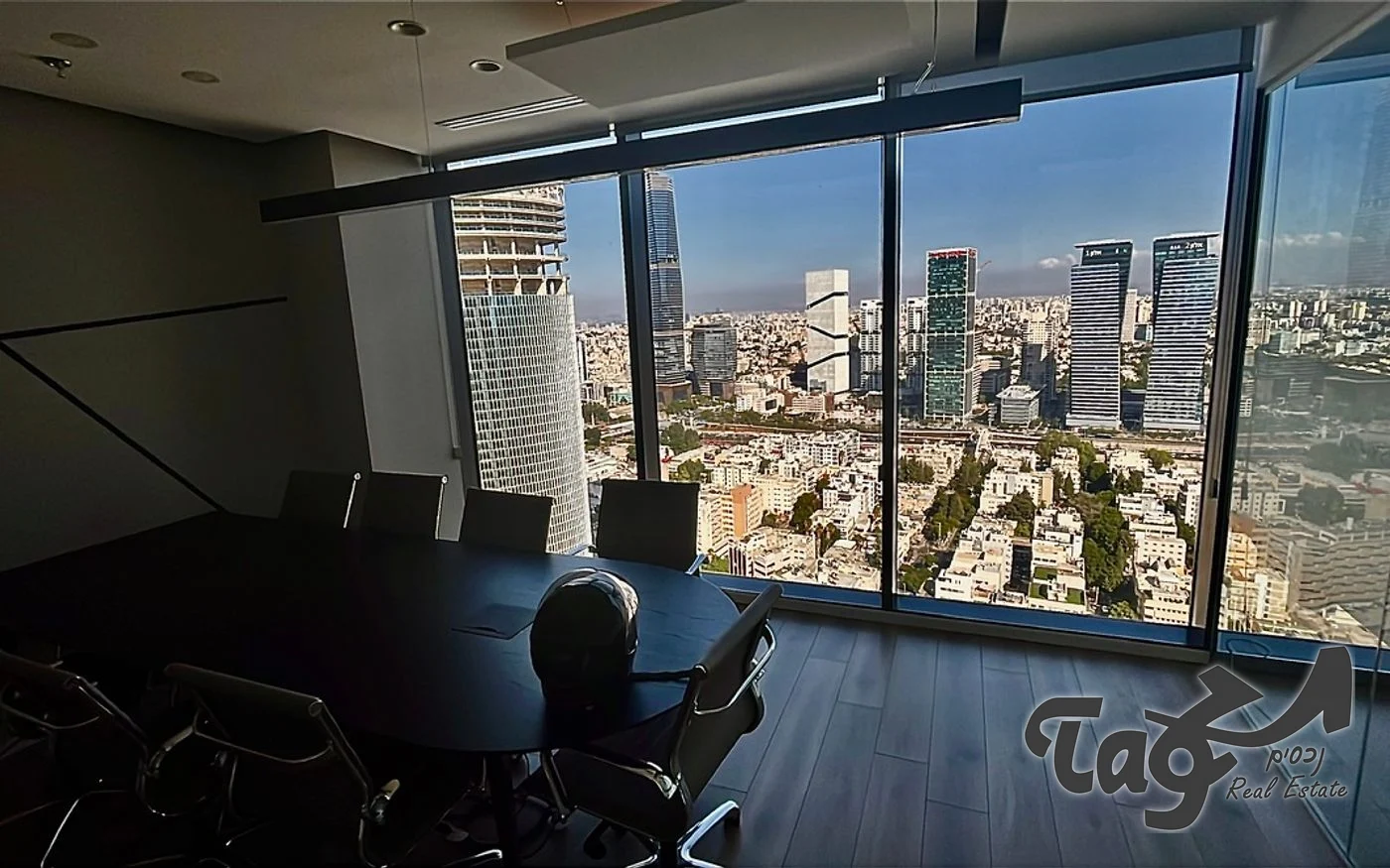 חדר ישיבות עם שולחן כהה, חלונות מהרצפה לתקרה ונוף פנורמי למגדלי העיר